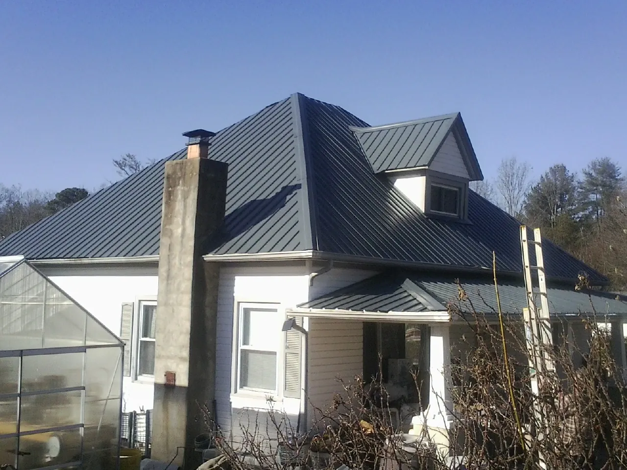 Dark blue standing seam metal roof on a white farmhouse with dormer — Slate & Tile Roof Repair by Roofing Brothers in La Conner