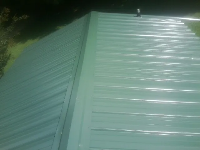 New green metal panels meeting at the ridge of a roof — Flat Roof Repair work by our crew in La Conner