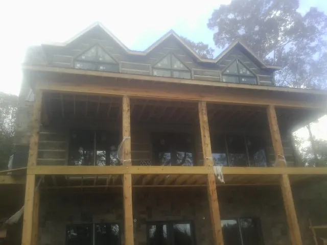 Dormers and porch framing on a large log home under construction — Roof Coating work by our crew in La Conner
