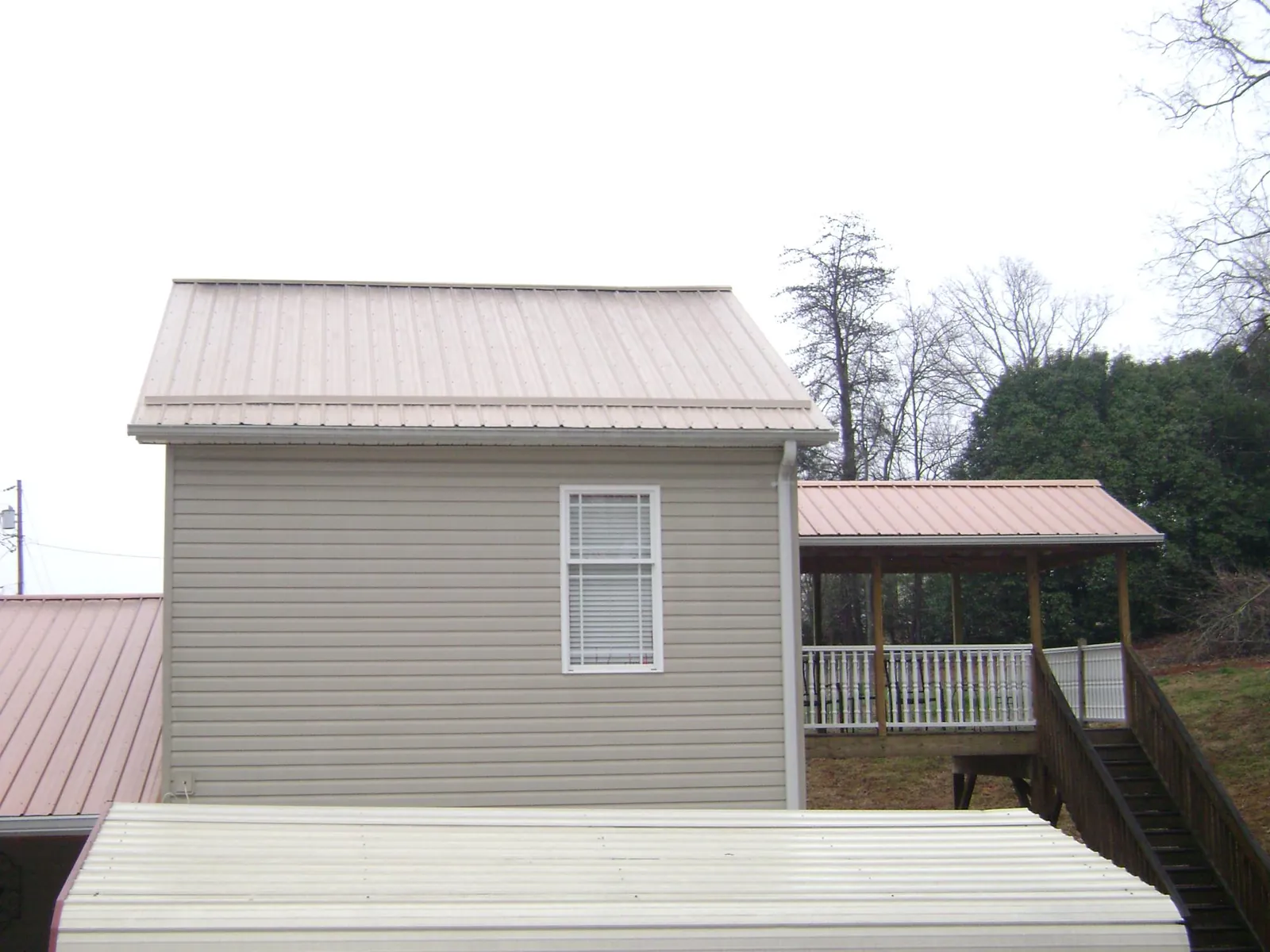 Tan metal roofs on a two story addition and attached porch, from a Roof Replacement job in La Conner