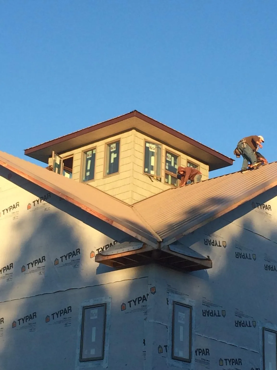 Roofers working around a rooftop cupola on a new metal roof at sunset — Roof Waterproofing in La Conner by Roofing Brothers